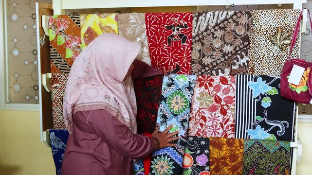 Muslim woman in hijab choosing traditional batik fabric
