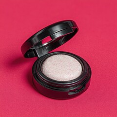 A single black compact of shimmering rose gold eyeshadow rests open on a textured pink surface.