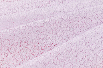 beautifully folded in straight folds of white guipure fabric on a pink background. a small pattern of floral ornament of the material. A copy space.