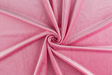 Chic velvet fabric in pink delicate color twisted in a spiral. elegant folds of soft velvet. layout for design, advertising of the product. top view