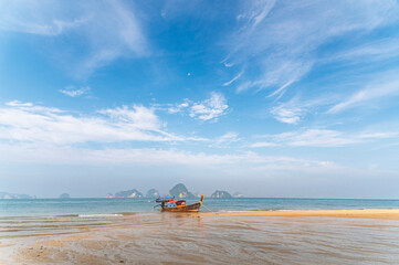 Traditional Thai longtail boat anchored on a peaceful tropical beach with Hong Island blue lagoon background, krabi, Thailand