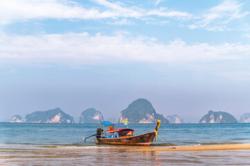 Traditional Thai longtail boat anchored on a peaceful tropical beach with Hong Island blue lagoon background, krabi, Thailand