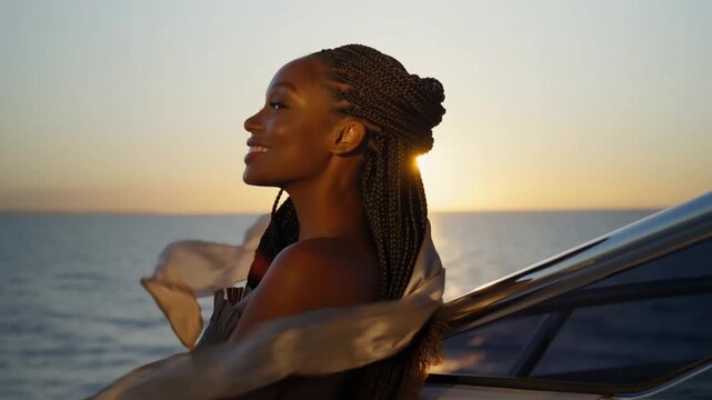Beautiful afro-american woman with braided hair leaning against the yacht railing as her silk scarf flutters in the wind, concept of serene contemplation and freedom
