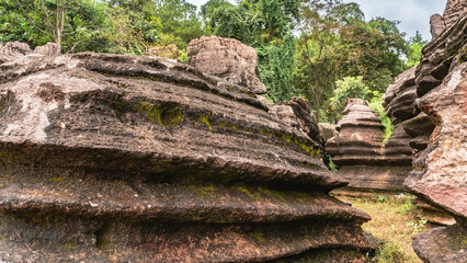 Unusual red-brown karst rocks. Bizarre outlines, layered structure with geological layers. Green...