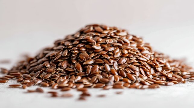 Brown seeds are arranged in a heap on a light background showing details of their surface and shape