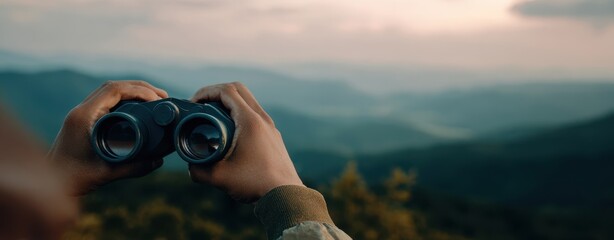 The binoculars in hands overlooking layered mountain landscape at dusk and twilight