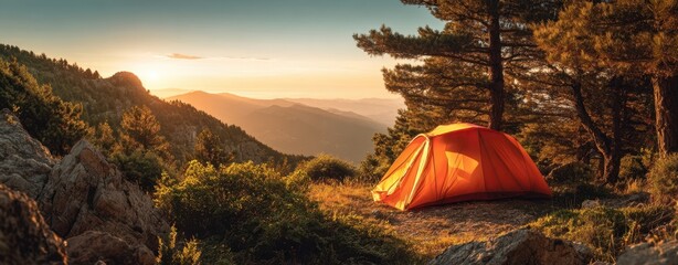 The tent glowing orange on a rocky ridge at sunset with panoramic mountain vista