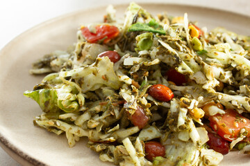A closeup view of tea leaf salad, on a plate.