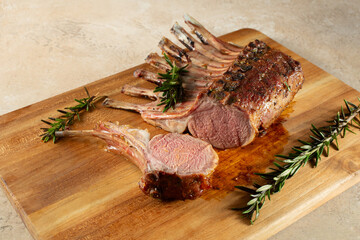A view of a medium rare lamb rack, on a wood board. © DAVID