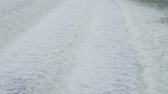 Water waves flowing over an artificial concrete weir forming a cascading waterfall. Dynamic river motion footage with textured water surface, natural flow patterns, and calming movement