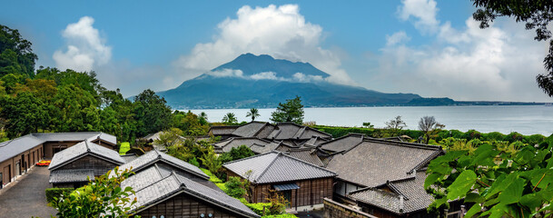 The roofs of ancient japanese houses with the iconic Sakurajima volcano in the background,...