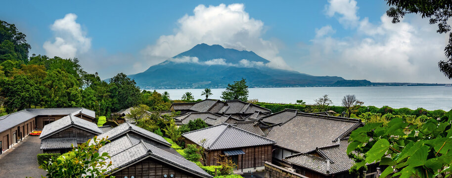 The roofs of ancient japanese houses with the iconic Sakurajima volcano in the background, Sengan-en, Kagoshima, Kyushu island, Japan
