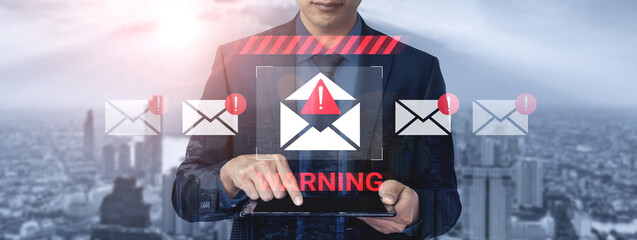 A businessman interacts with a tablet showing a warning alert for email security threats, highlighting the importance of vigilance in online communication in a modern city. Gantry