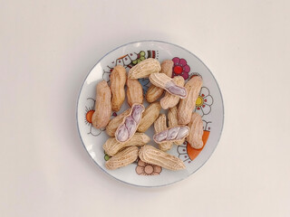 Top view of Boiled peanuts served on a plate on a white background.