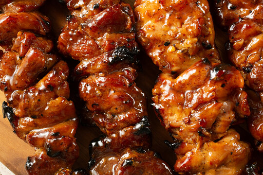 A top down view of a layer of BBQ pork and chicken skewers, as a background.
