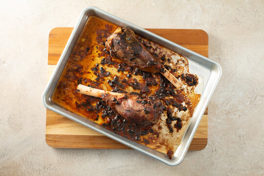 A top down view of a baking sheet of two roasted lamb shanks.