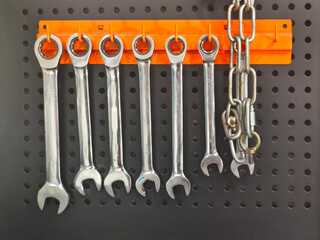 wrench set hanging on orange hanger over black board