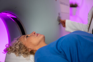Patient undergoing MRI scan with purple lighting and medical professional operating equipment