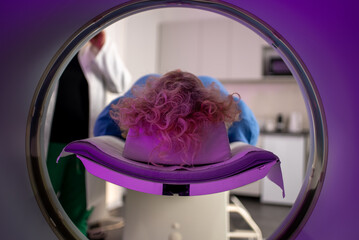 Patient undergoing MRI scan with technician in background, close-up view from inside the machine