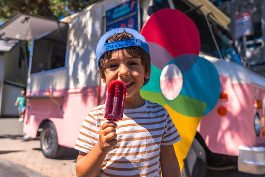 Happy child eating popsicle in front of food truck in vancouver