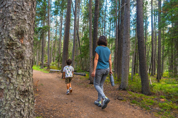 Fototapeta premium Mother and son hiking along scenic forest trail in banff national park