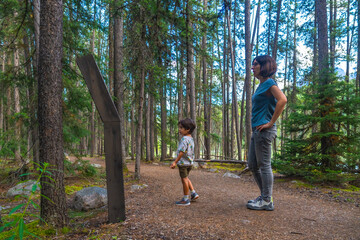 Tourists reading a sign in banff national park forest trail