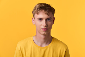 Young man in a yellow tee against a bright yellow backdrop, casual lifestyle image suitable for...