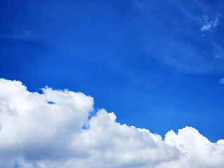Bright blue sky with fluffy white cumulus clouds at the bottom.