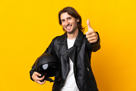 Man with a motorcycle helmet isolated on yellow background with thumbs up because something good has happened