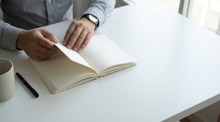 Man's Hands Flipping Through a Blank Notebook Open on a White Desk, Symbolizing the Process of Goal Setting and Planning for Future Success
