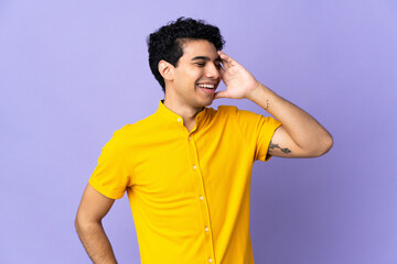 Young Venezuelan man isolated on purple background smiling a lot