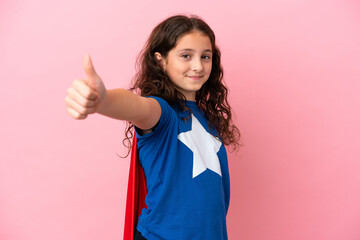 Little caucasian girl isolated on pink background in superhero costume with thumb up © luismolinero