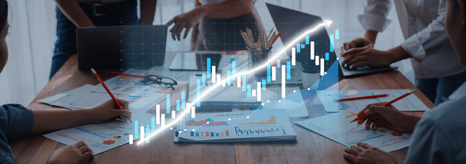 A dynamic business team works collaboratively in an office setting, analyzing financial data with digital graphs while discussing strategies and insights for growth. Axiom