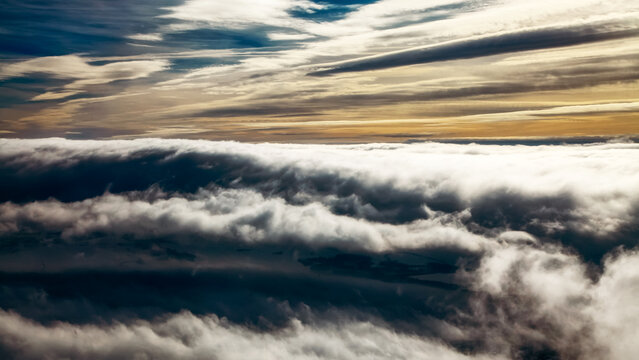 Dramatic cloud inversion above landscape with layered clouds and moody sky at sunrise