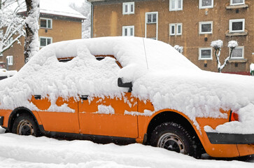 Car completely covered by fresh snow during heavy winter snowfall in residential area