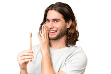 Young handsome man brushing teeth over isolated background whispering something