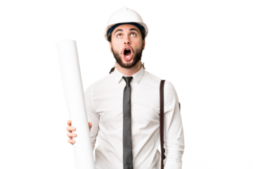 Young architect man with helmet and holding blueprints over isolated chroma key background looking up and with surprised expression