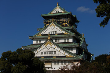Fototapeta premium Osaka Castle Osaka-jo: A Japanese Fortress With Green Roofs Against a Clear Blue Sky