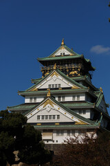 Naklejka premium Osaka Castle Osaka-jo: A Japanese Fortress With Green Roofs Against a Clear Blue Sky