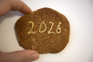 Gingerbread cookie with calendar date number 2026 text on white background with hand. Festive...