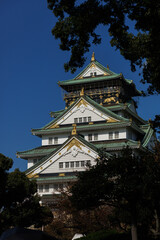 Fototapeta premium Osaka Castle Osaka-jo: A Japanese Fortress With Green Roofs Against a Clear Blue Sky