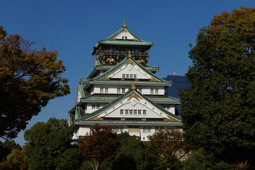 Naklejka premium The Osaka-jo Castle Tower in Japan, with White Walls and a Green Roof, Against a Clear Blue Sky