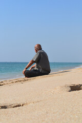Fototapeta premium Elderly Man Sitting by the Beach and Enjoying the Moment