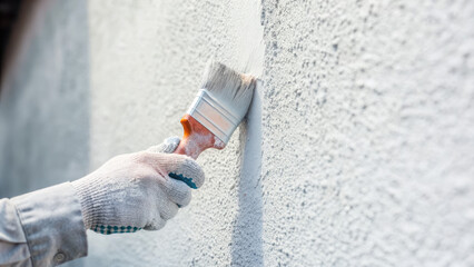 Close-up of gloved hand painting at site concept. Person painting a wall with a paint roller in bright colors.