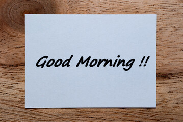 The words "Good Morning" are written on a piece of white paper on a wooden table.