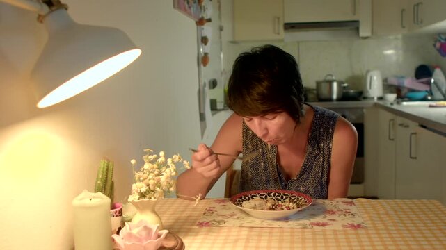 caucasian woman slurping noodles at cozy table lamplight casual outfit enjoying flavorful bowl savoring mouthful