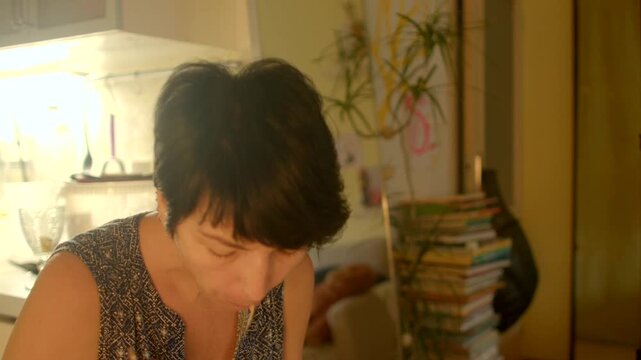 woman taking quick lunch break at cluttered desk with books and lamp, hurried spoonfuls and focused posture, warm study