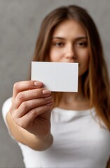 Young woman holds a clean, blank white business card in front of her, offering a space for your design and branding.