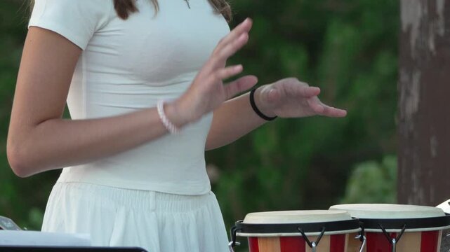 Bongo drums, playing, woman performing rhythmic music outdoors with percussion instruments