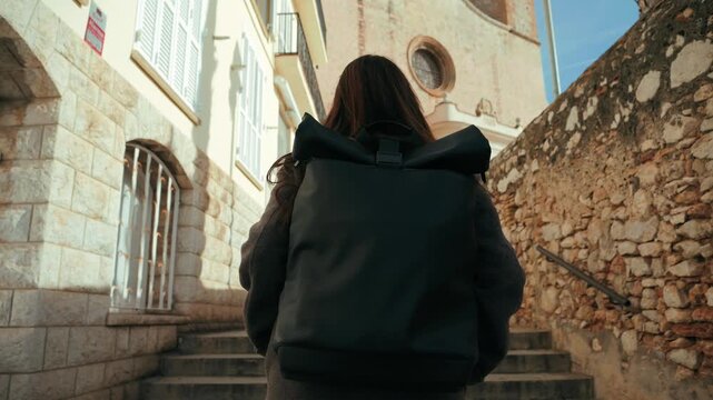 Female pilgrim with backpack on a journey for religious or spiritual reasons, simply a wanderer enjoys the views of the city's attractions. High quality 4k footage